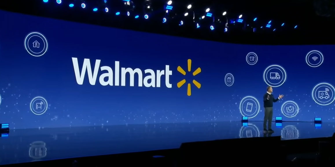 Man on stage with walmart logo behind him