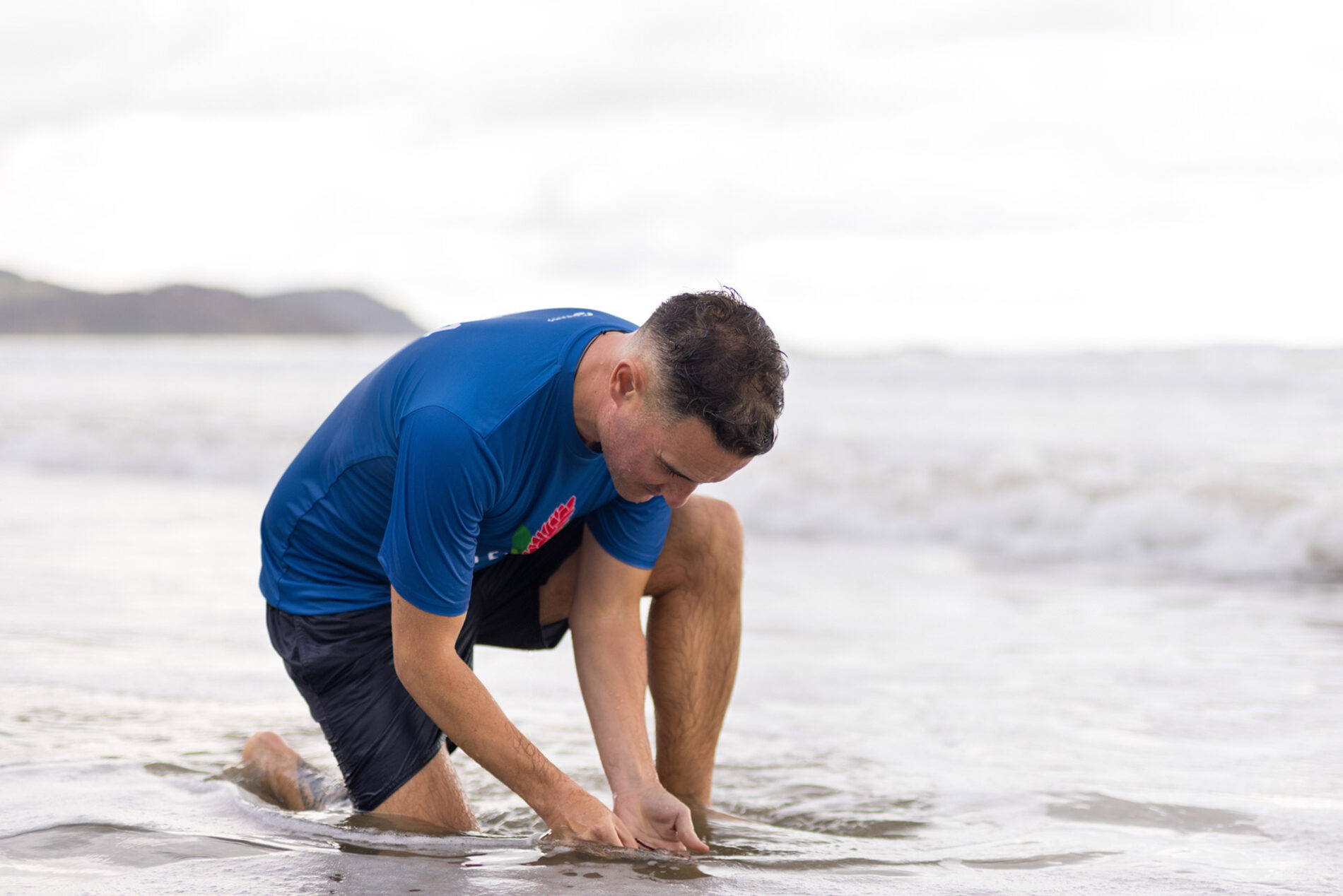 Photo of Dan putting hands into the sand