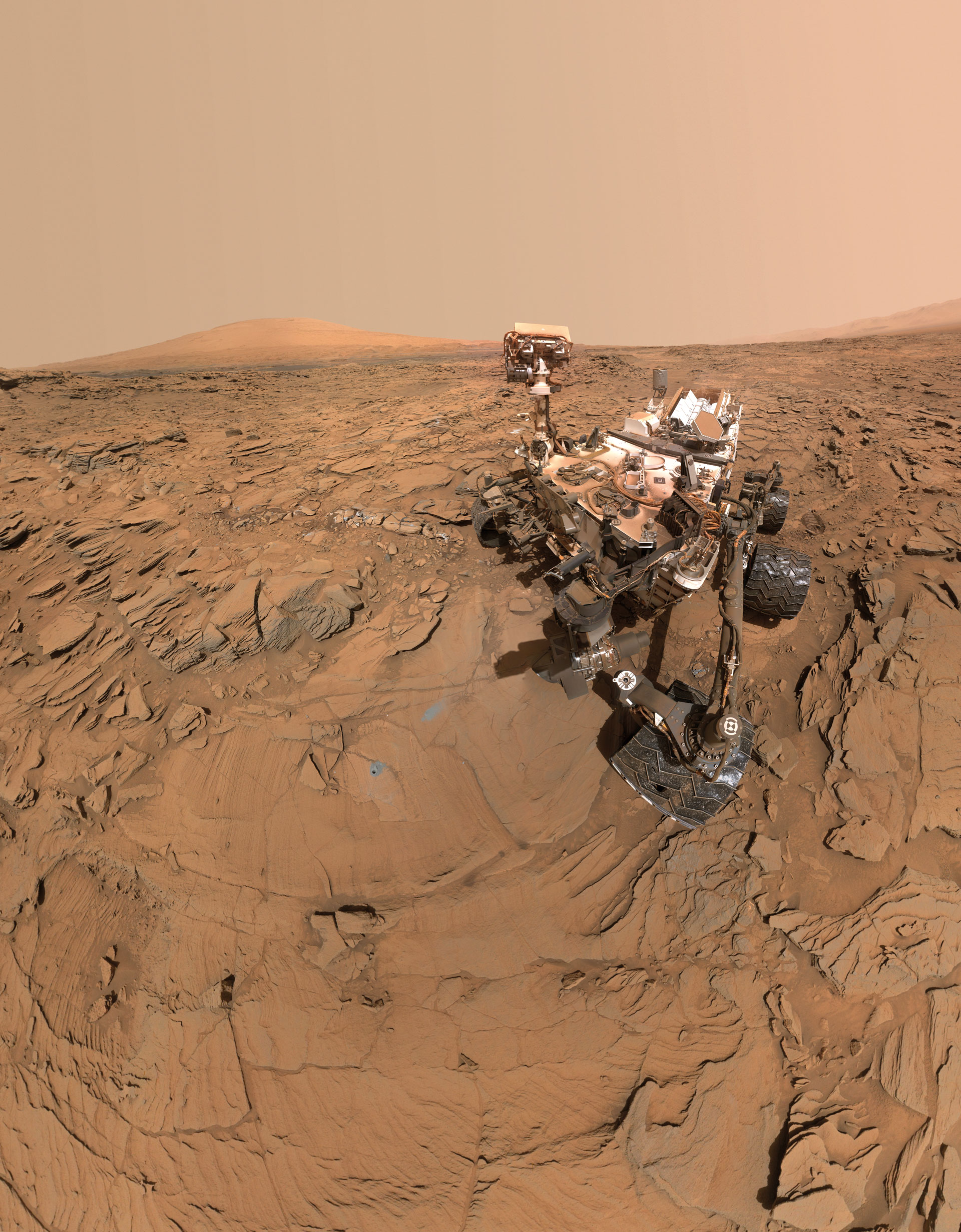 Mars rover on rocky, reddish Martian terrain under a dusty sky. The rover's camera arm is extended, capturing detailed images of the surface and surrounding landscape.