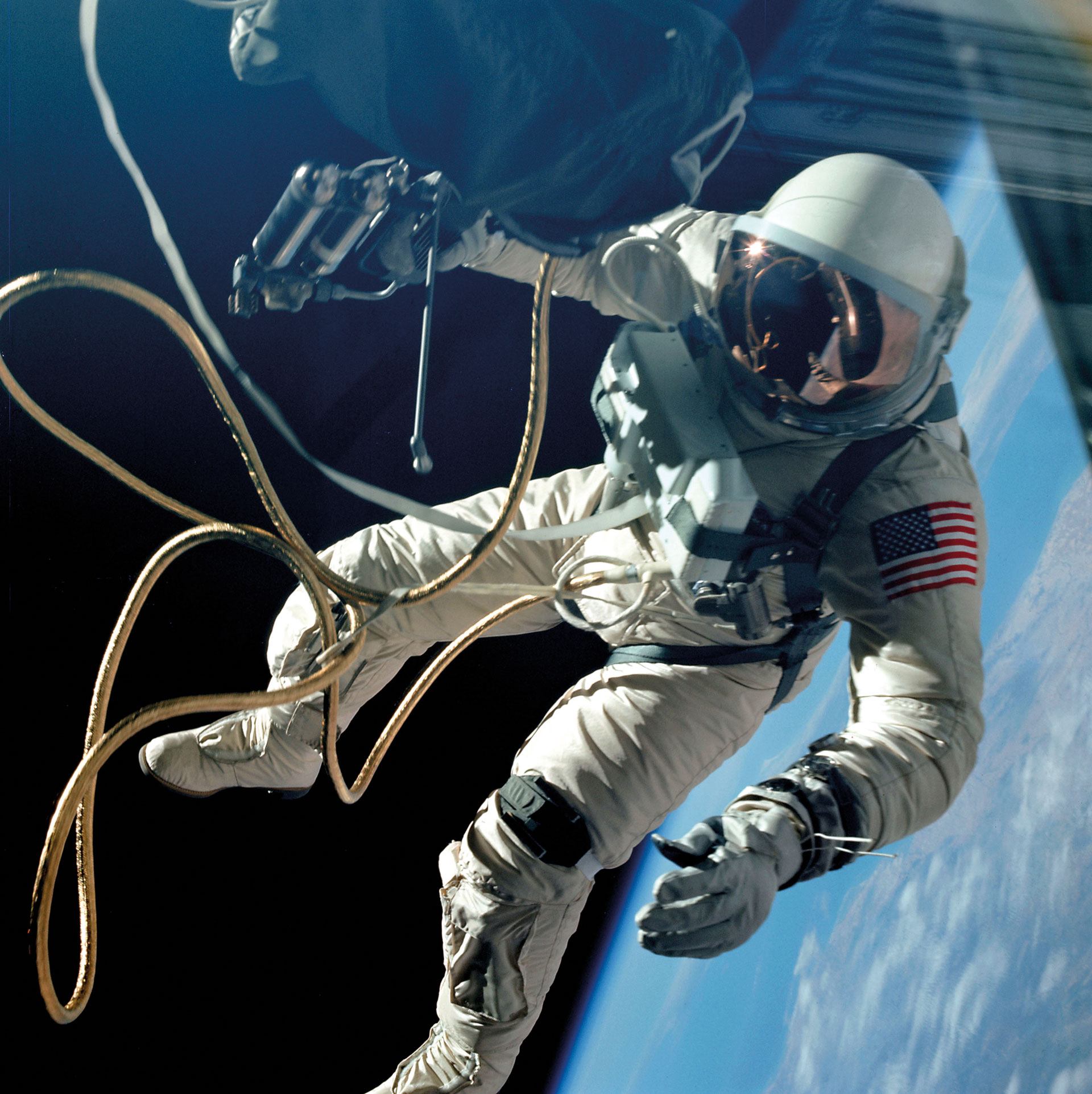 An astronaut in a white spacesuit floats outside a spacecraft above Earth, holding onto a gold safety tether with one hand, with the planet visible in the background.