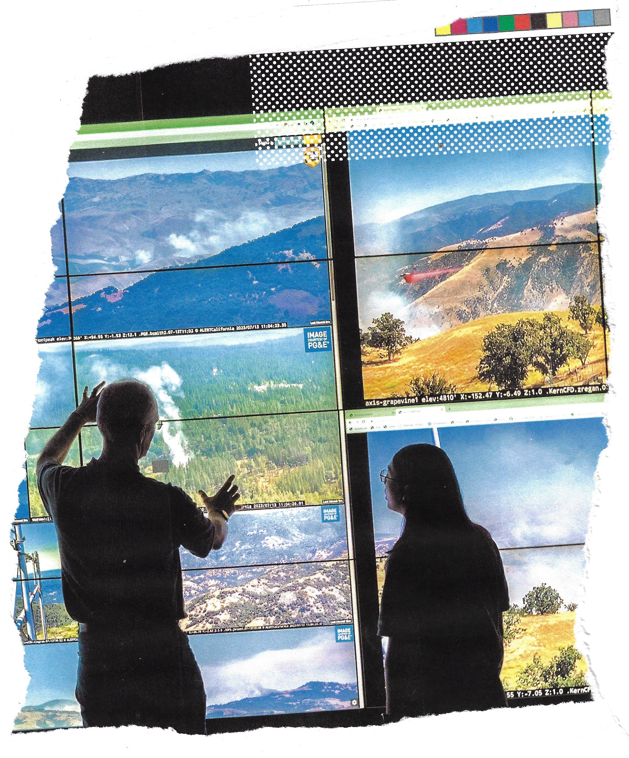 Two people in silhouette view a large multi-screen display showing live aerial footage of California wildfires in mountainous terrain.