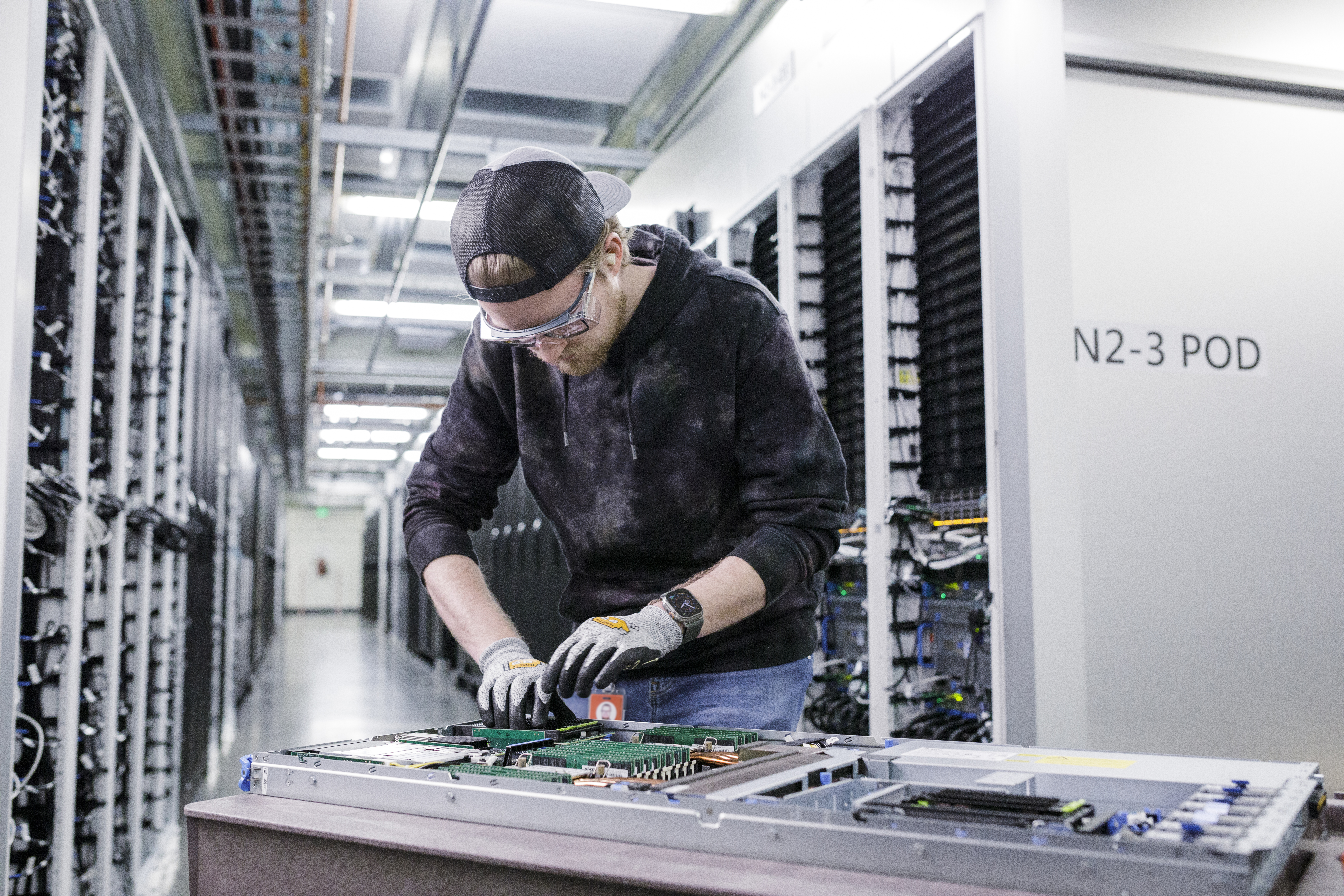 A man works on a server rack inside a datacenter.