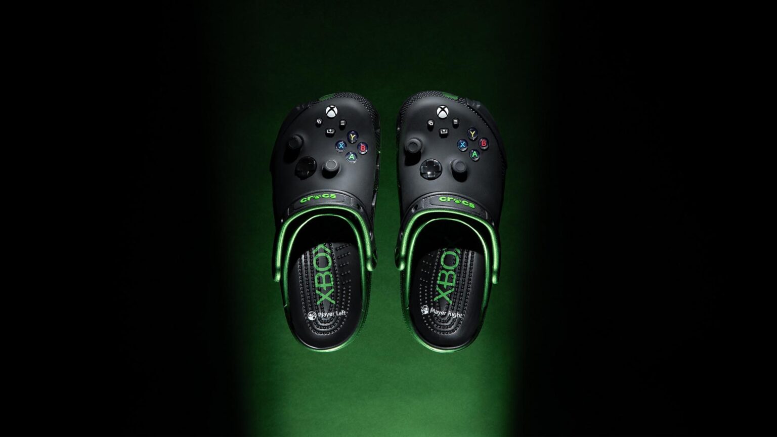 Pair of black Xbox-themed Crocs with green accents and controller button designs on top.