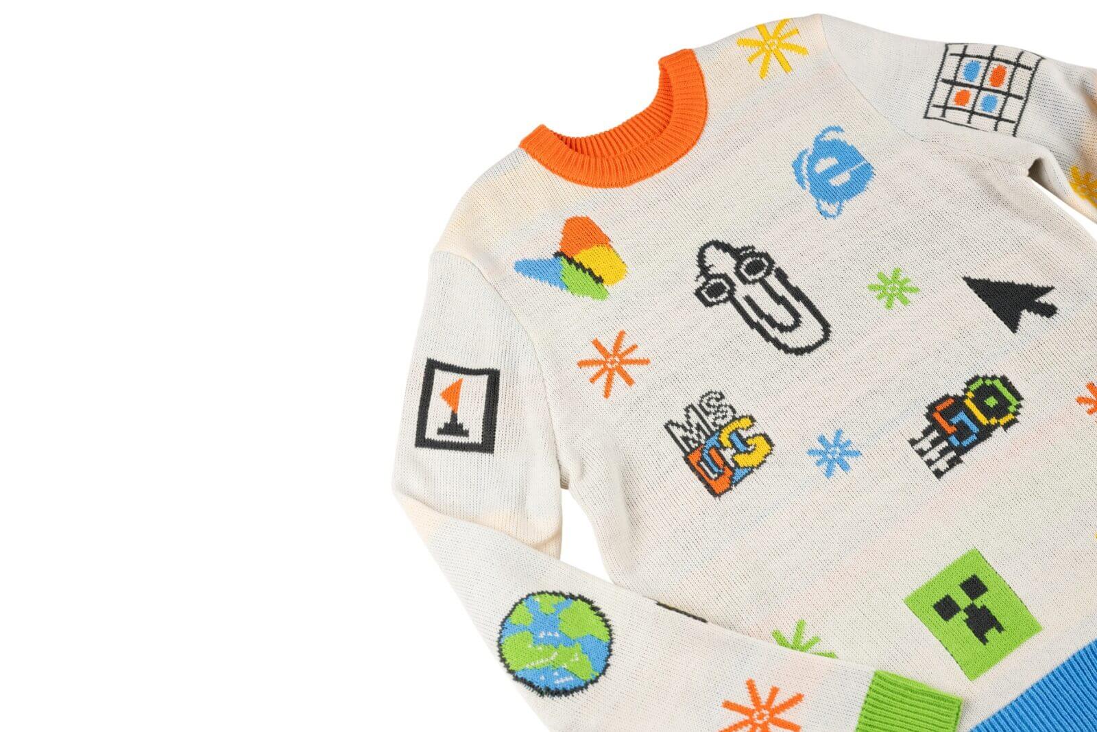 White holiday sweater with colorful retro Microsoft icons, including Clippy, Internet Explorer logo, Paint palette, and pixel art designs.