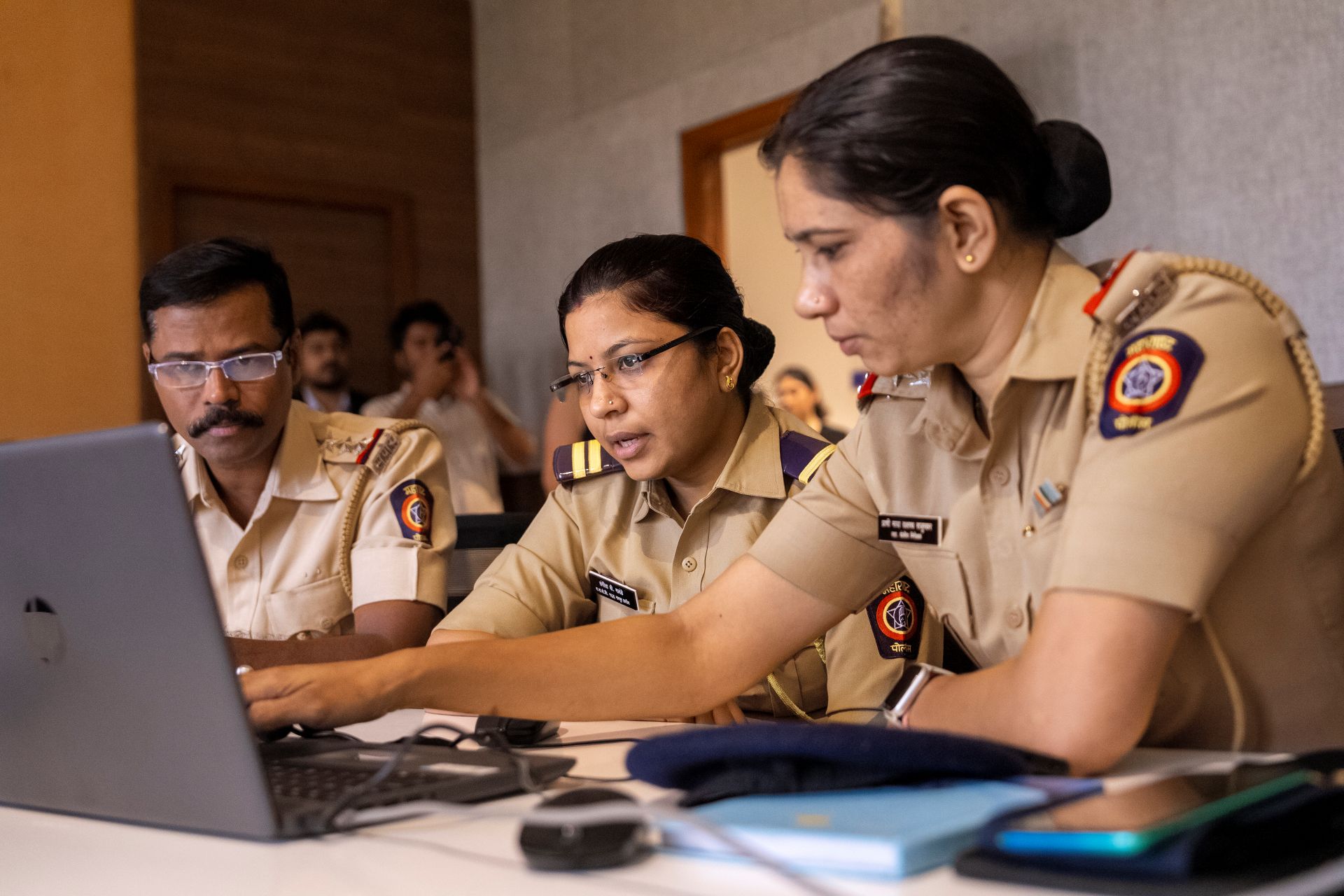 Police officers in uniform working together on a laptop at a desk.