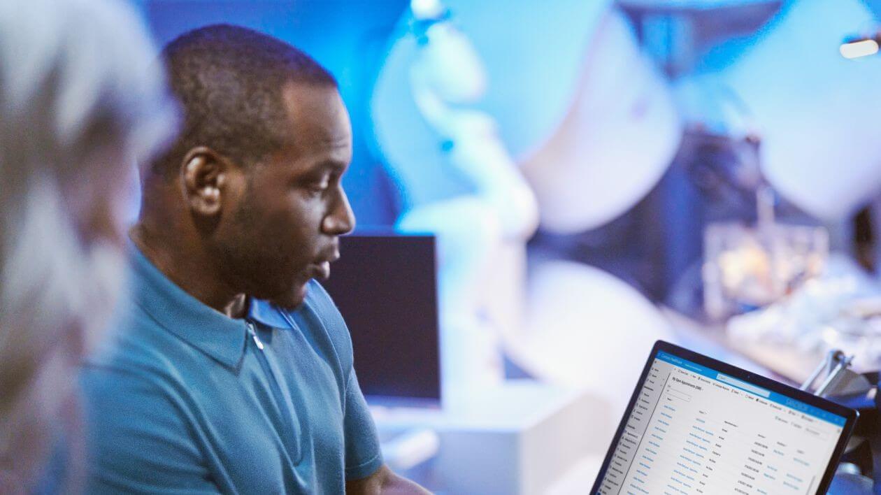 Person working on a laptop with data displayed on the screen in a tech lab setting.