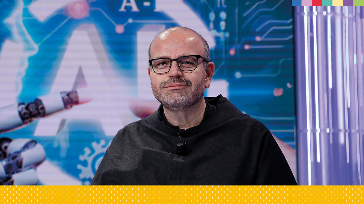 person in hoodie seated in studio with AI-themed backdrop