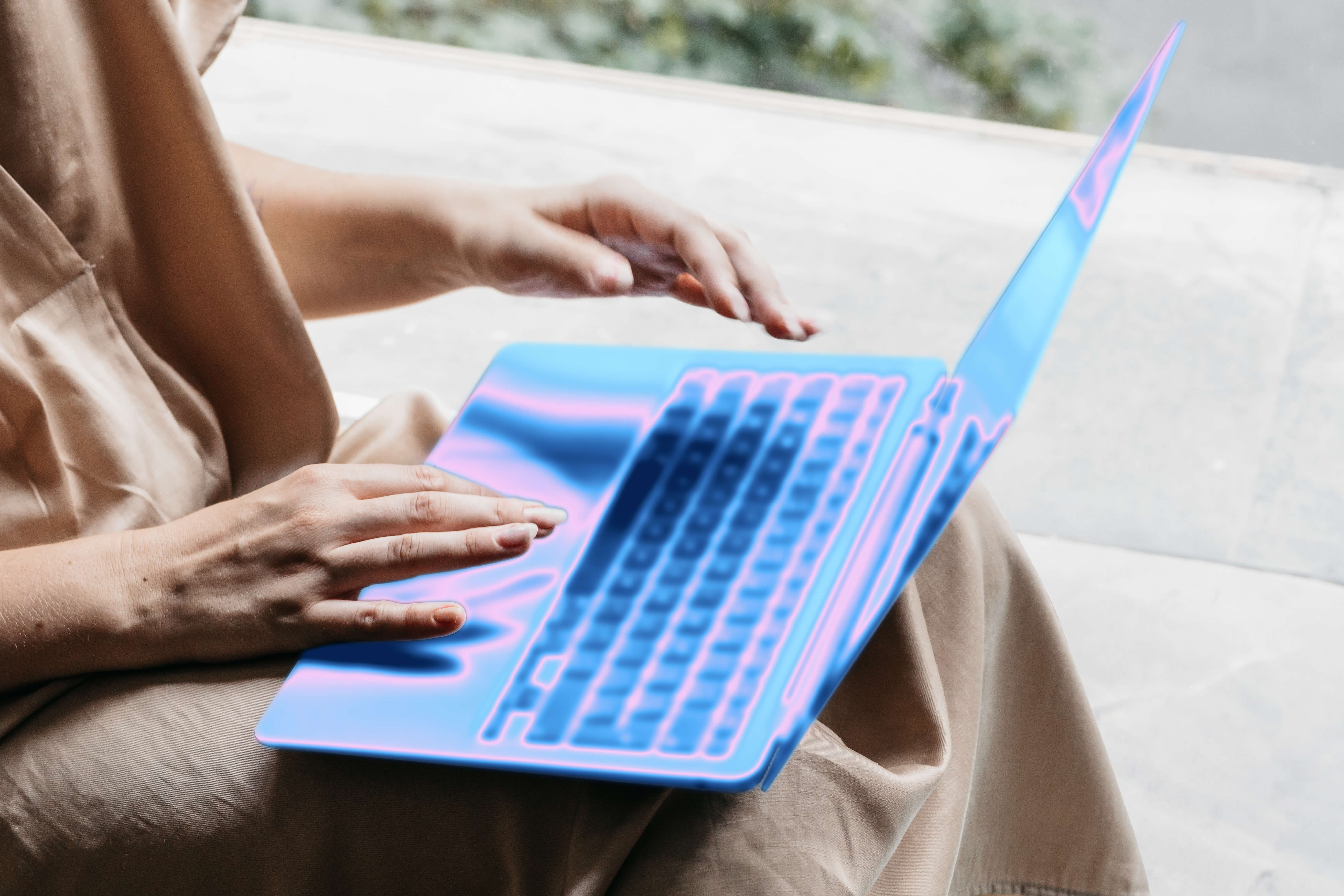 Hands hovering over a laptop with a blue, glowing digital overlay.