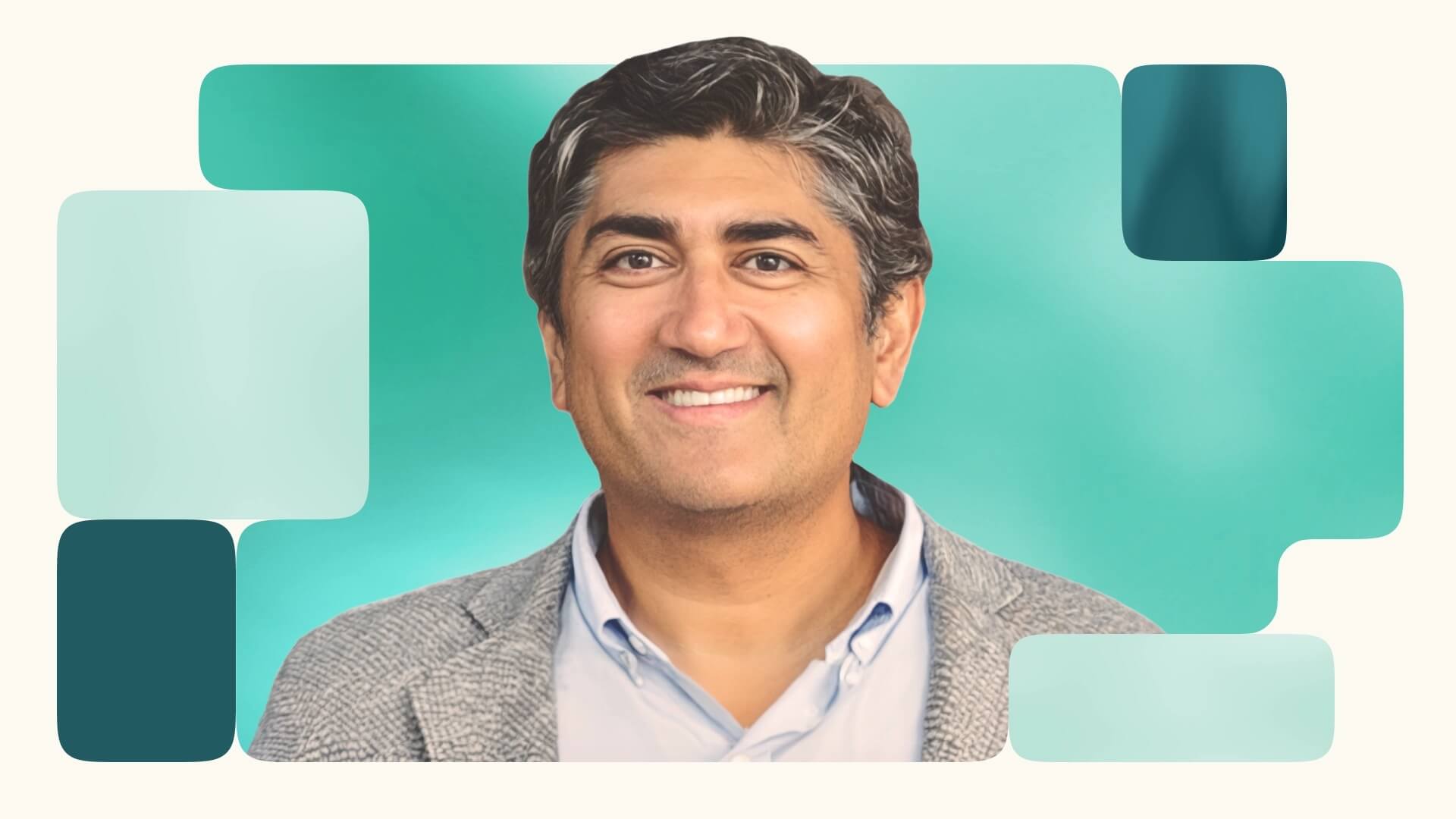 Smiling man in a blazer against a teal background.