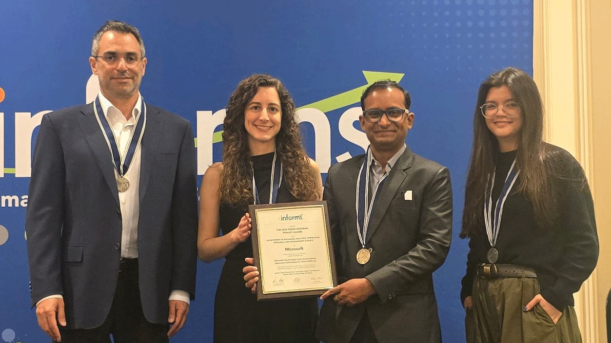 Four people holding an award certificate and medals at an event.