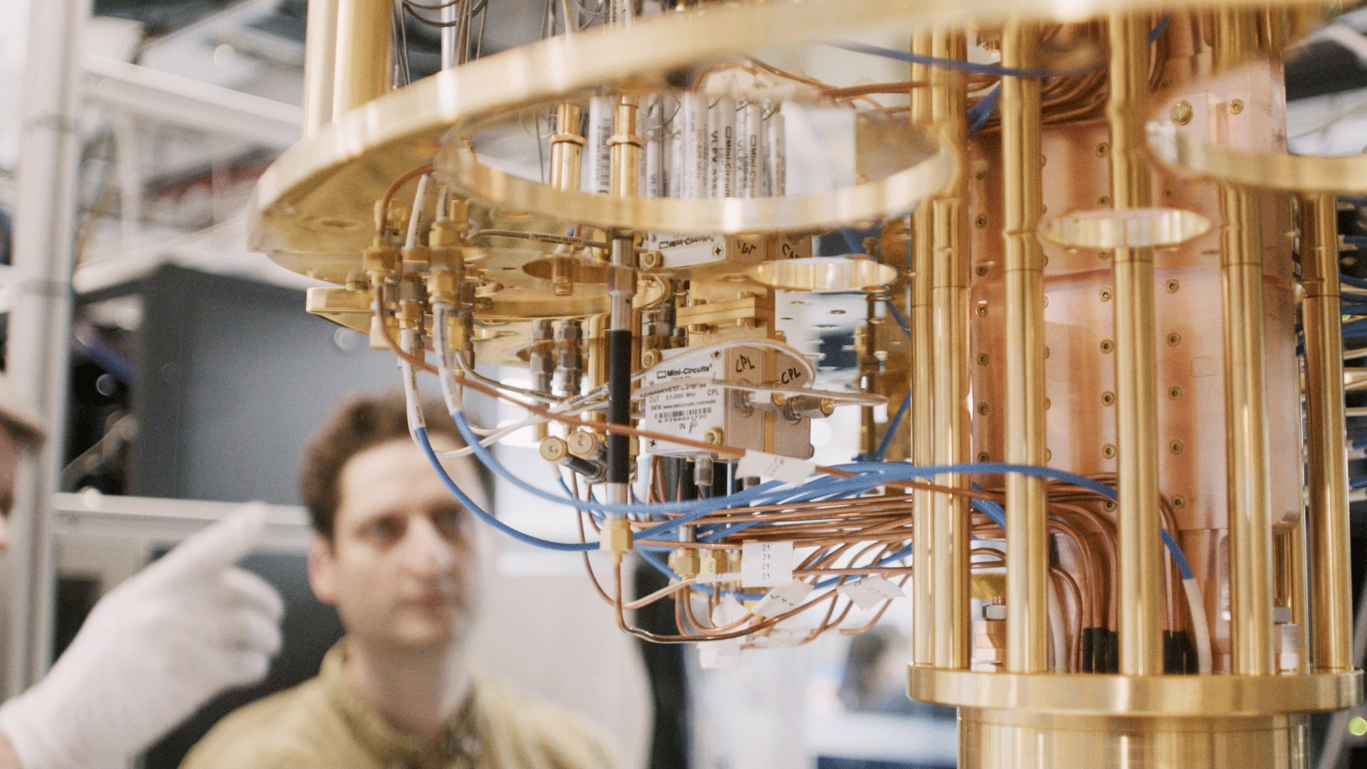 Close-up of a quantum computing system with gold wiring and components inside a lab.