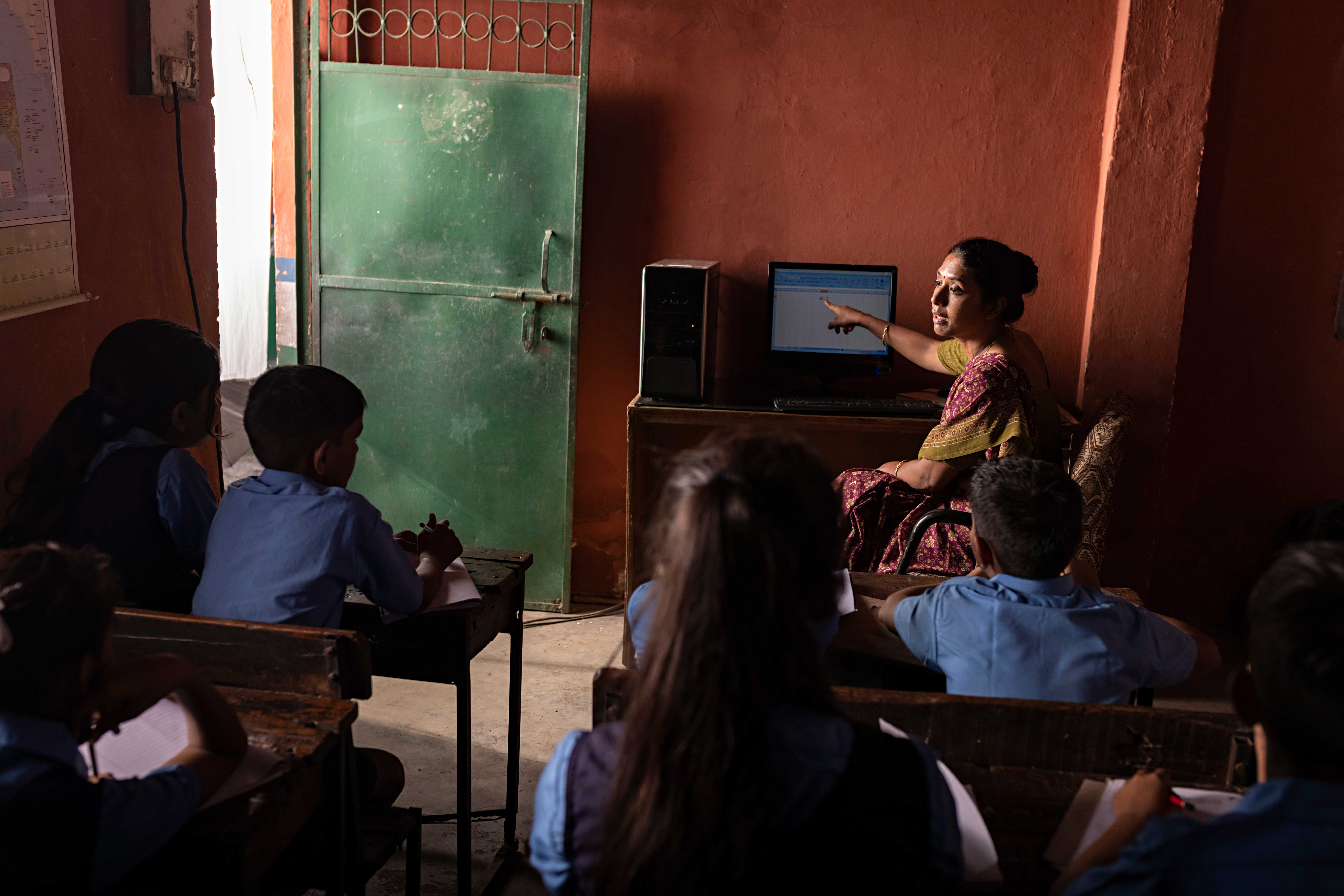 Teacher teaching students in a classroom on desktop PC