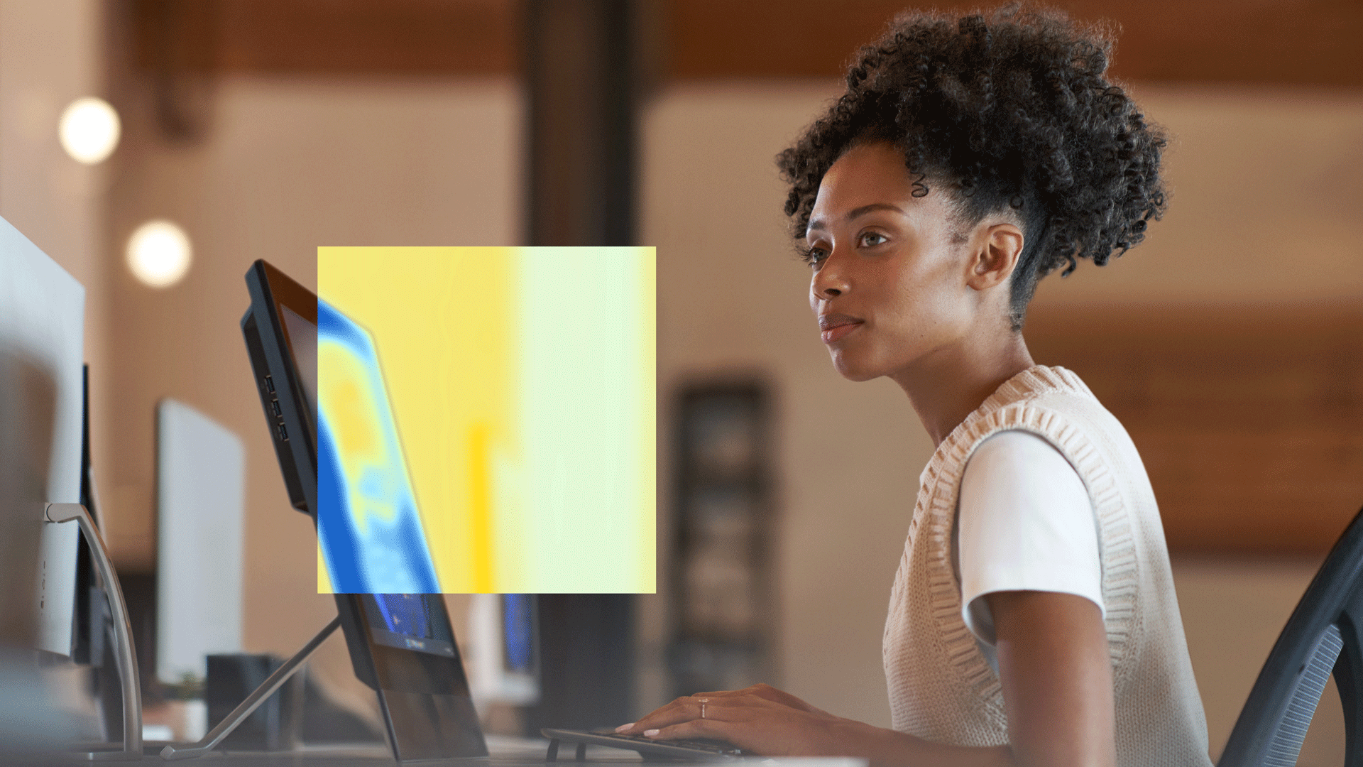 Person seated at a desk using a desktop monitor, with a colorful heatmap overlay on the screen.