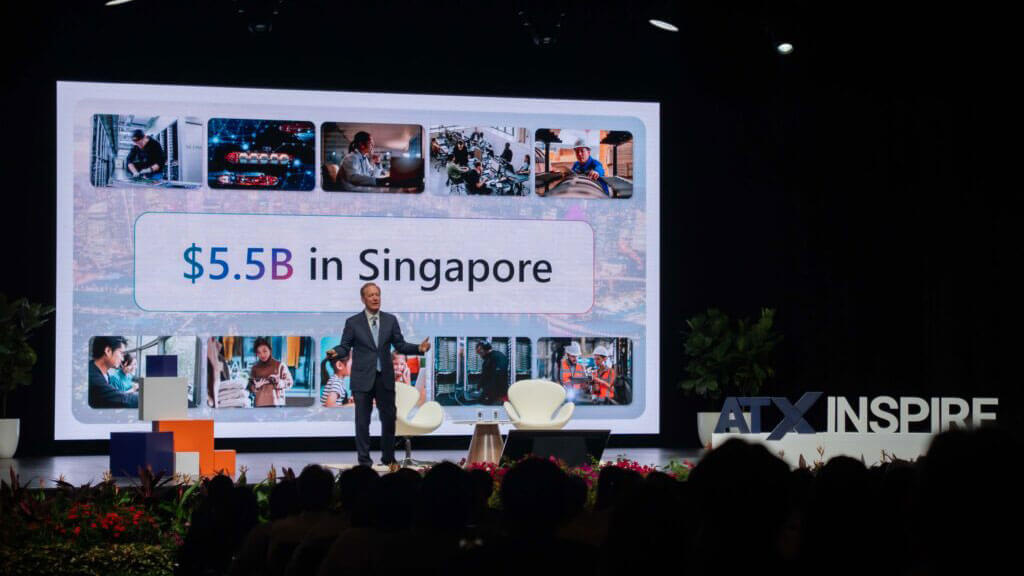 Speaker on stage before a screen reading "$5.5B in Singapore."