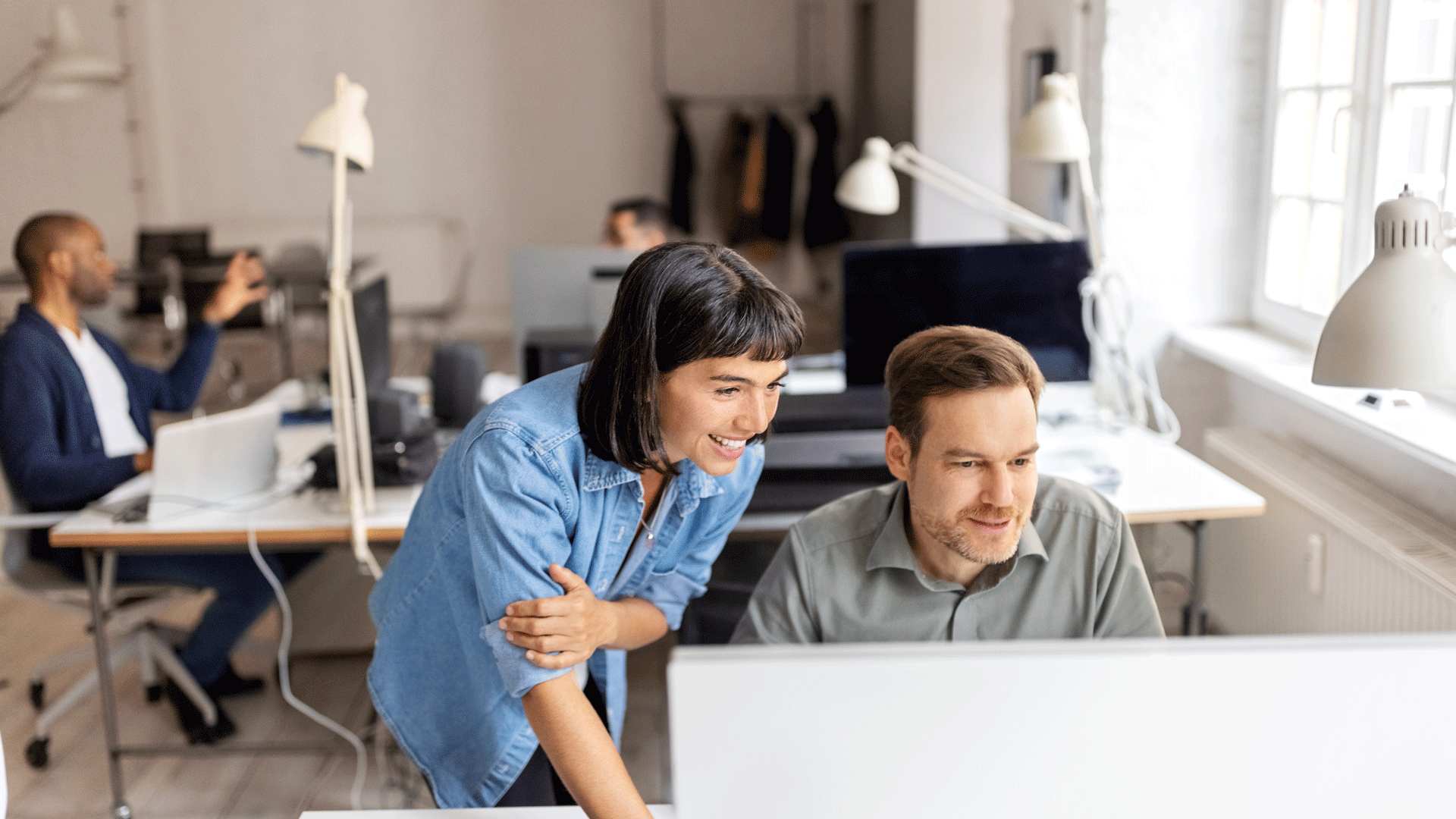 People collaborating at computers in an open-plan office.