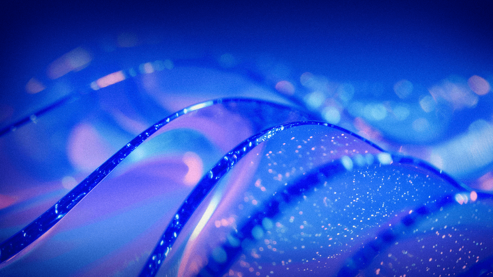 Abstract blue and purple waves with glowing particles and soft light effects.
