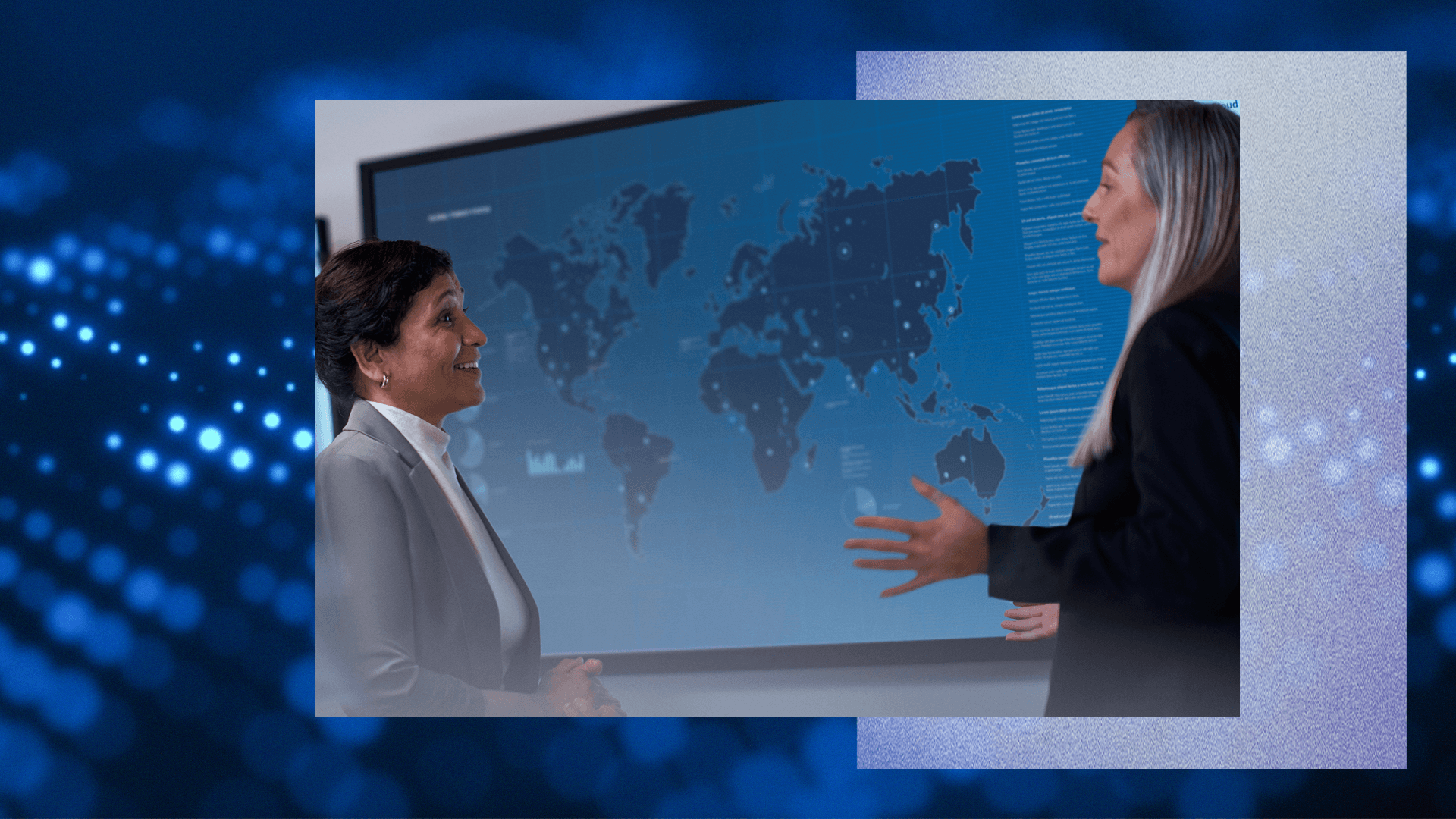 Two people in discussion in front of a large digital world map display.