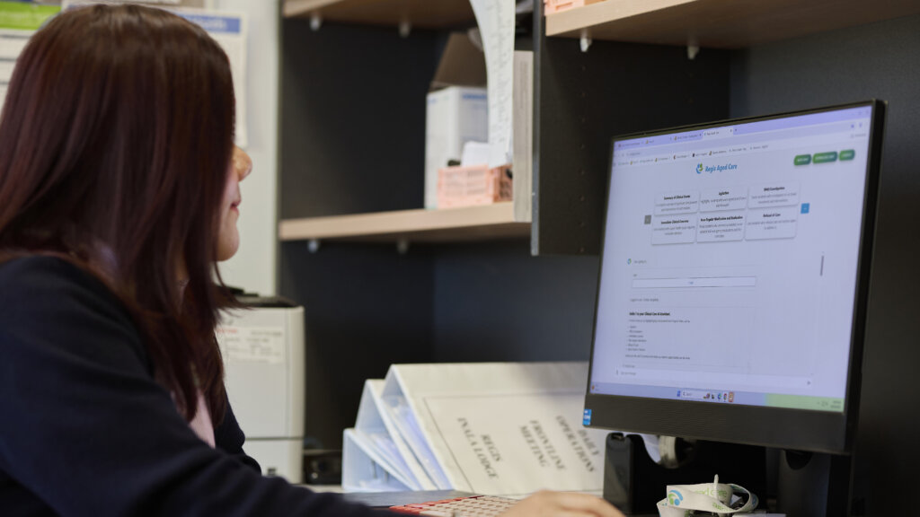 Person seated at a desk viewing a computer monitor in an office.