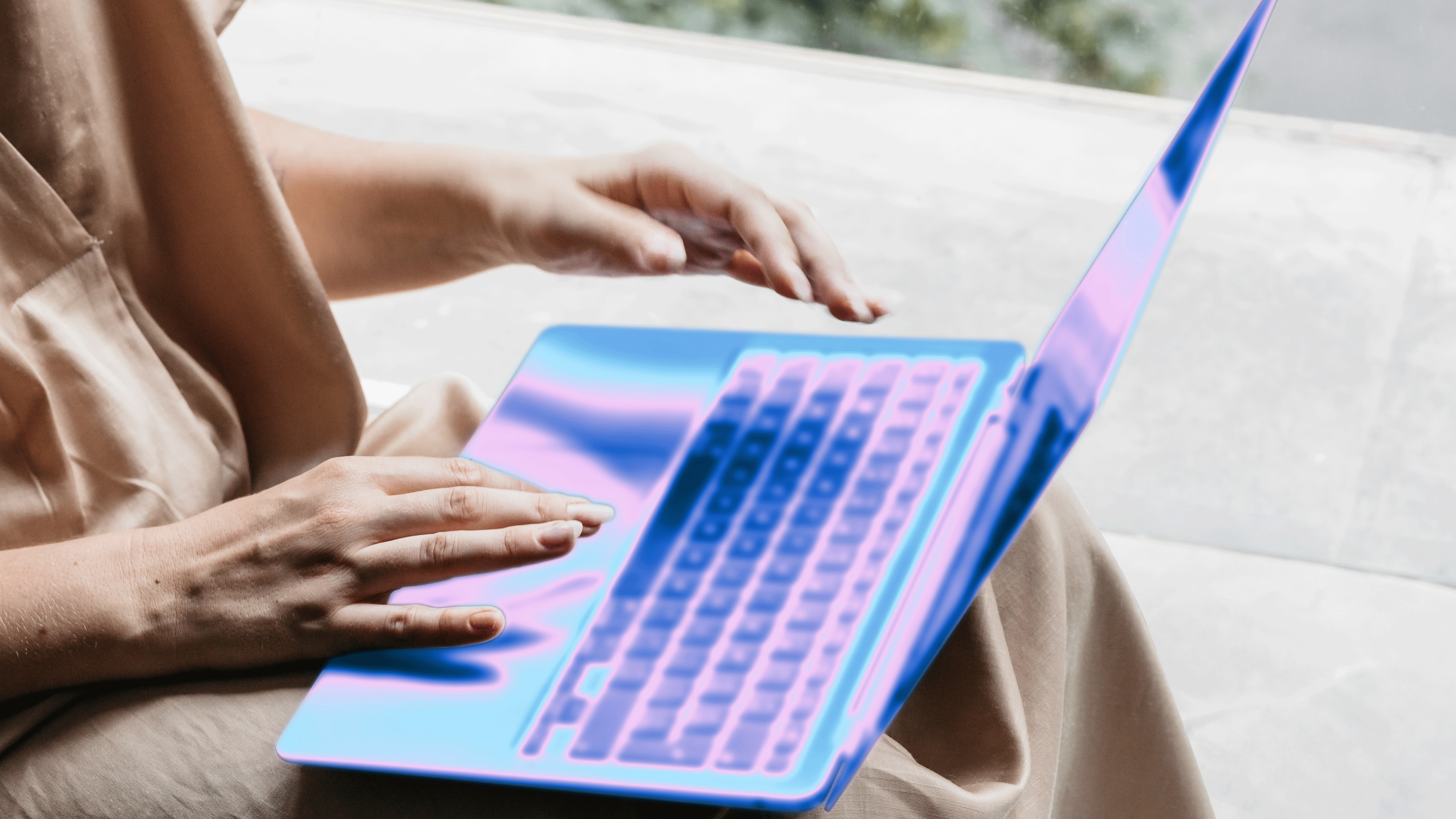 Person using a laptop with a glowing, abstract digital overlay.