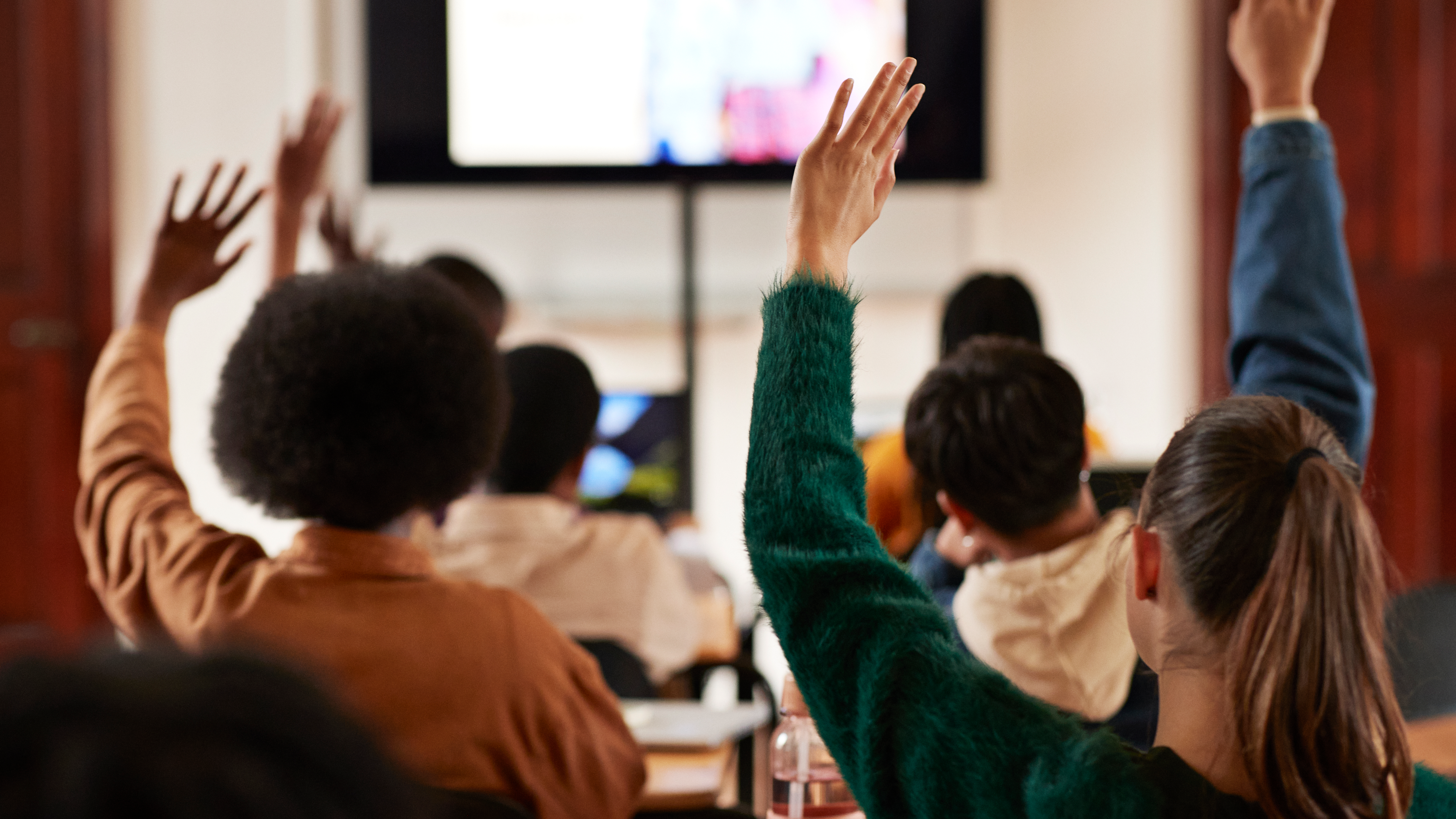 Students raise their hands in a South African classroom.