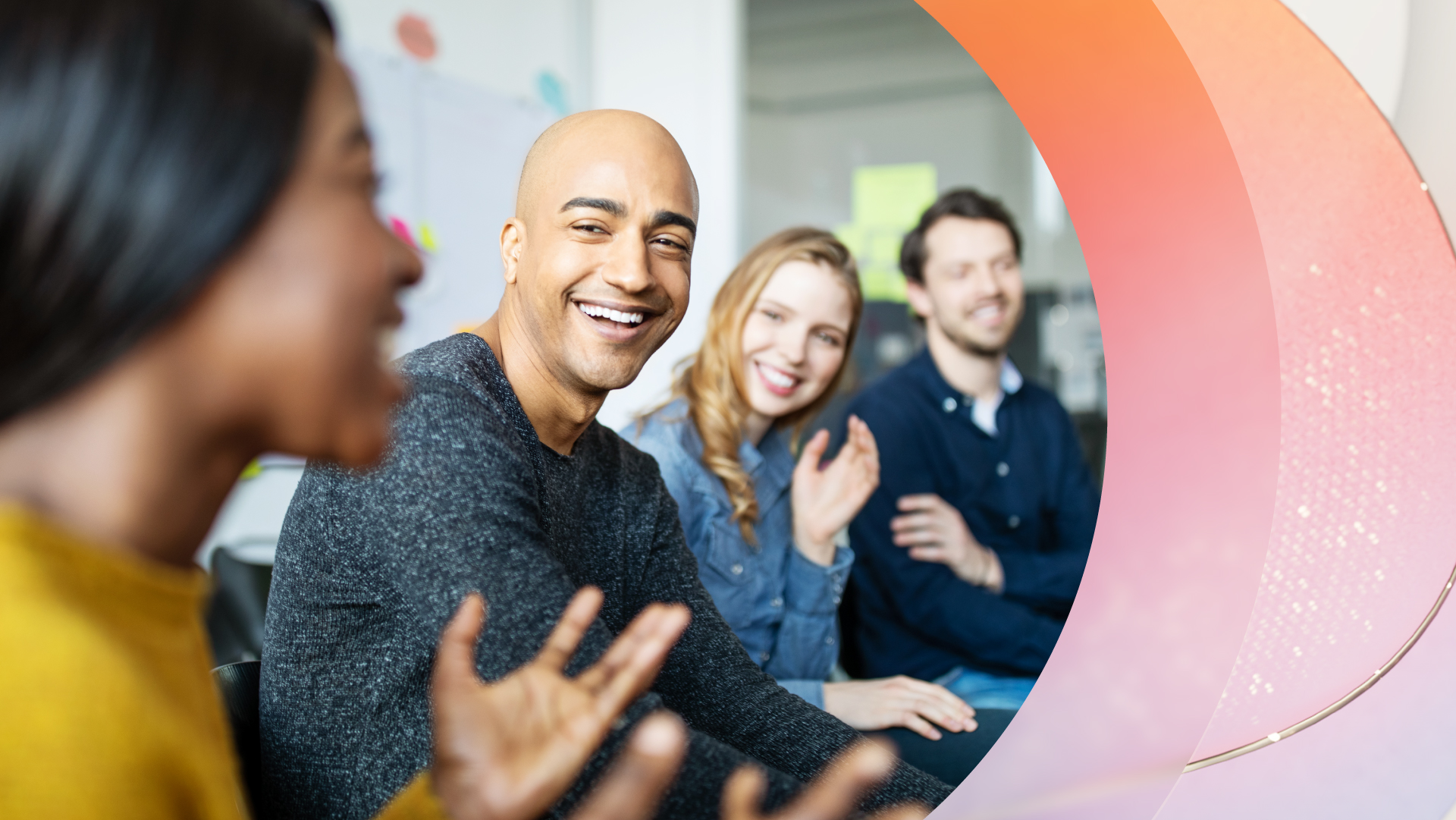 Group of people in a meeting, one speaking while others listen and smile.