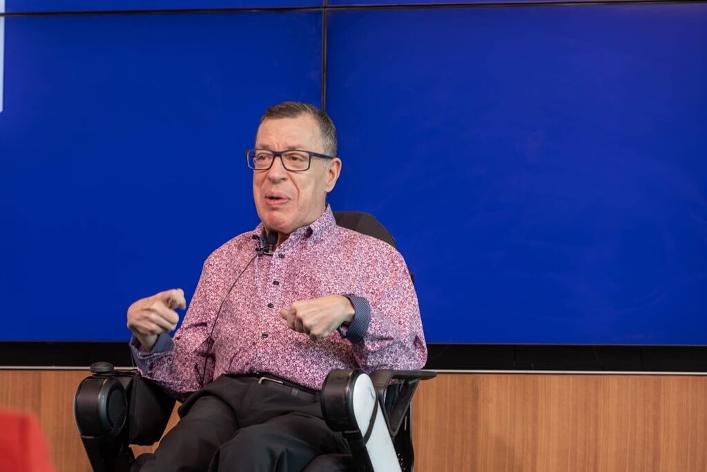 Dame onstage, presenting against a blue screen.