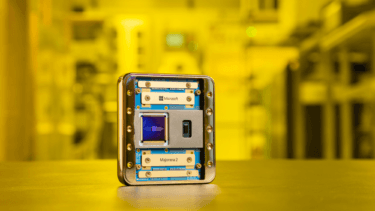 Close-up of a Microsoft “Majorana 2” device with a visible chip inside, set against a yellow lab background.