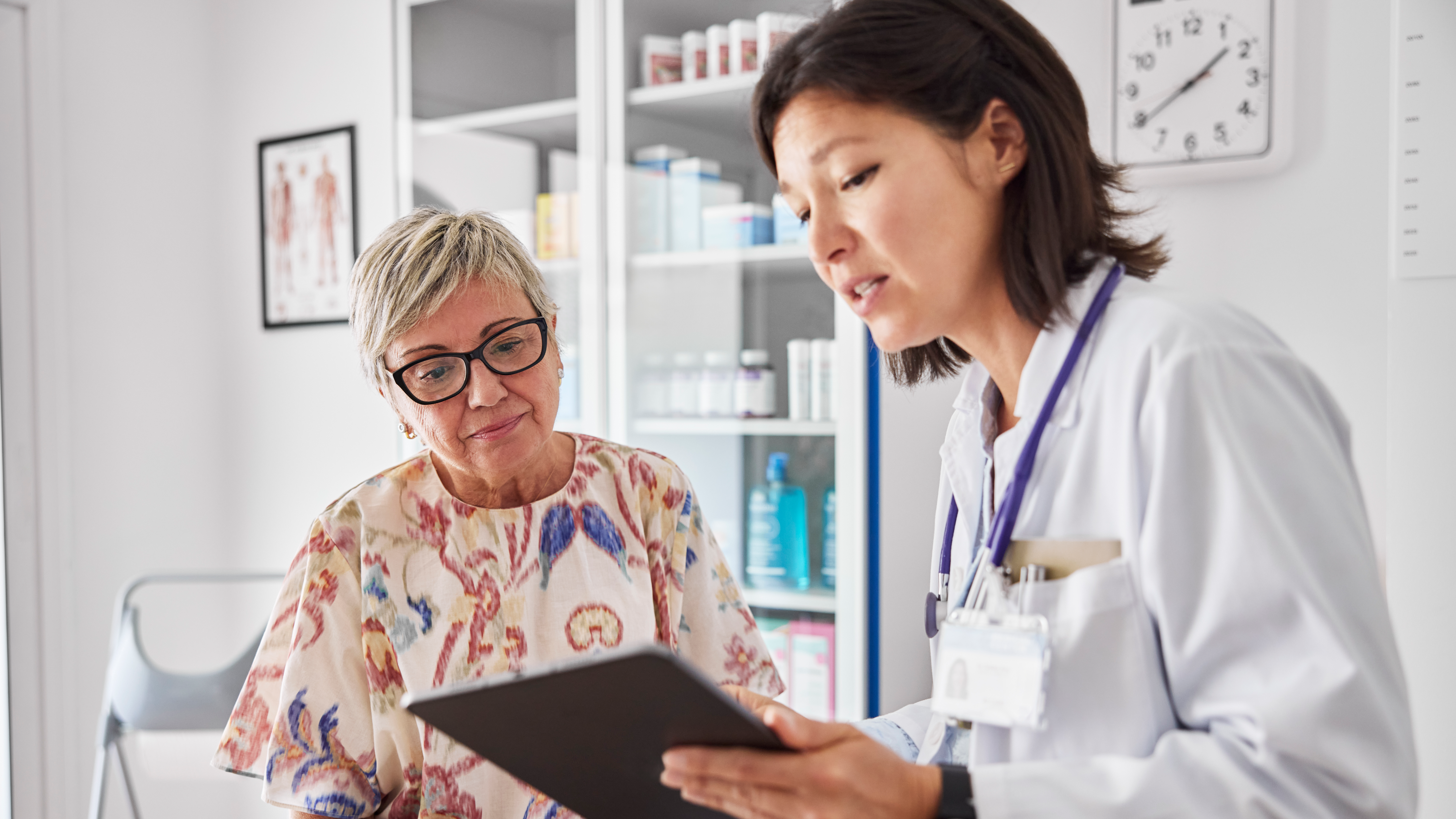 Clinician reviews tablet with patient in exam room.