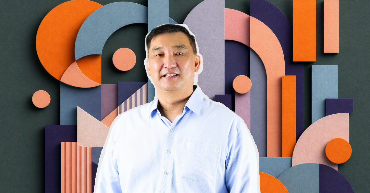 Alt text: Person in a light blue shirt in front of a colorful geometric abstract background with overlapping circles, arches, and rectangles in orange, blue, and purple tones.