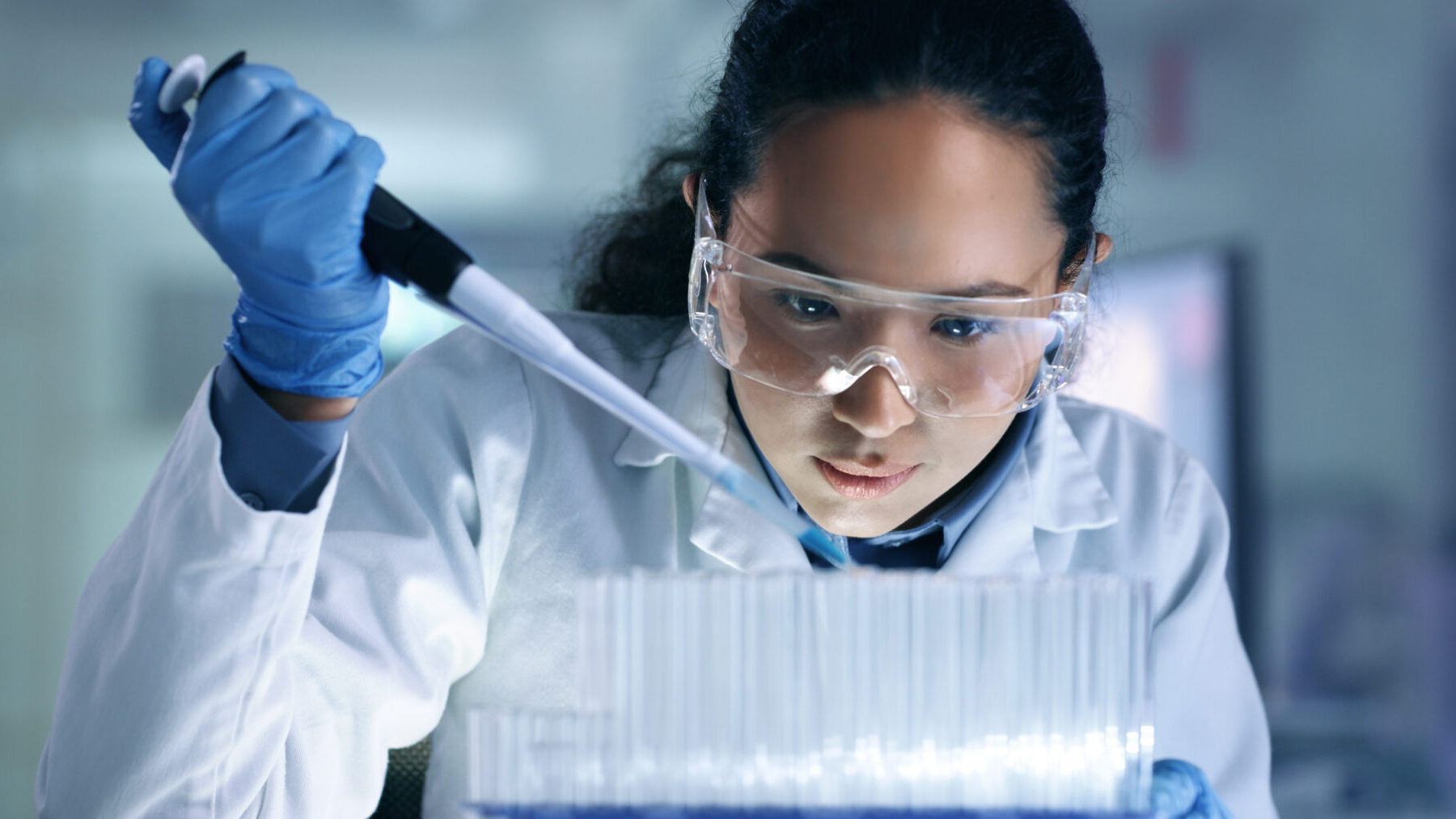 Scientist using a pipette to transfer liquid in a laboratory.
