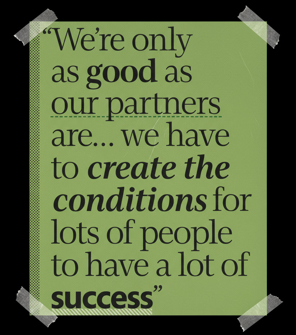 Green poster taped at the corners, featuring the quote: "We're only as good as our partners are... we have to create the conditions for lots of people to have a lot of success.