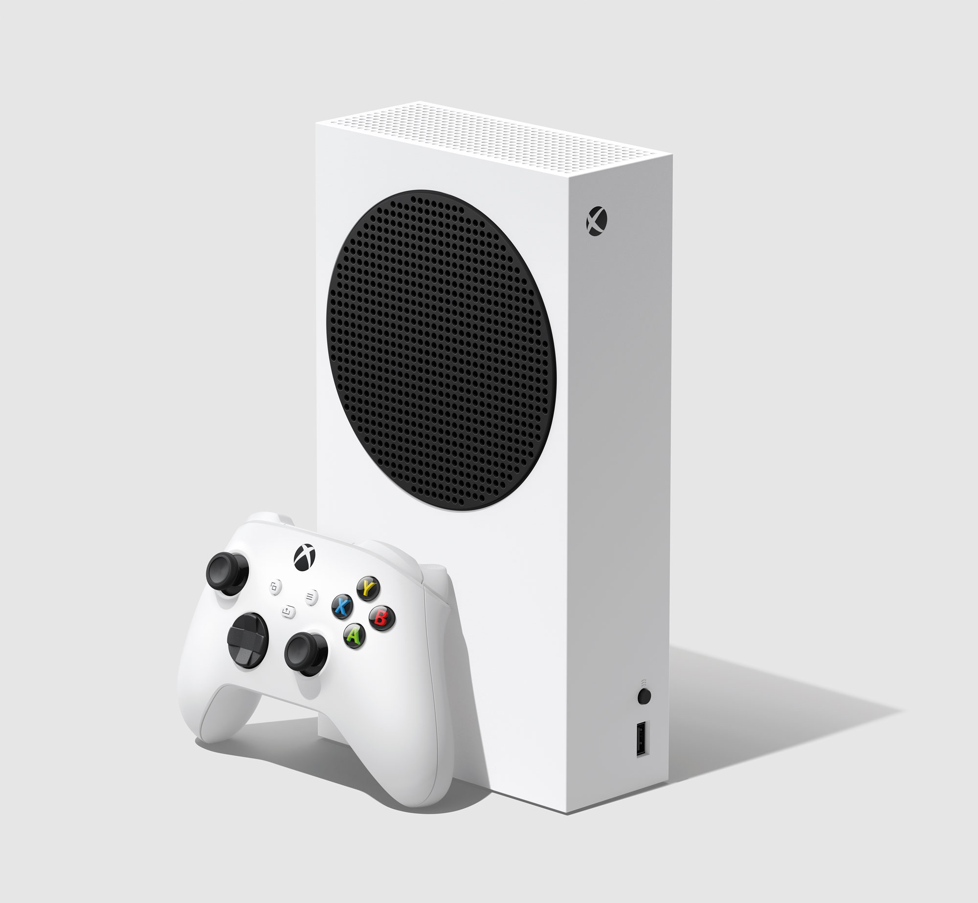 A white Xbox Series S gaming console stands upright next to a matching wireless controller on a plain light gray background. The console has a large black circular vent and the Xbox logo in the top corner.