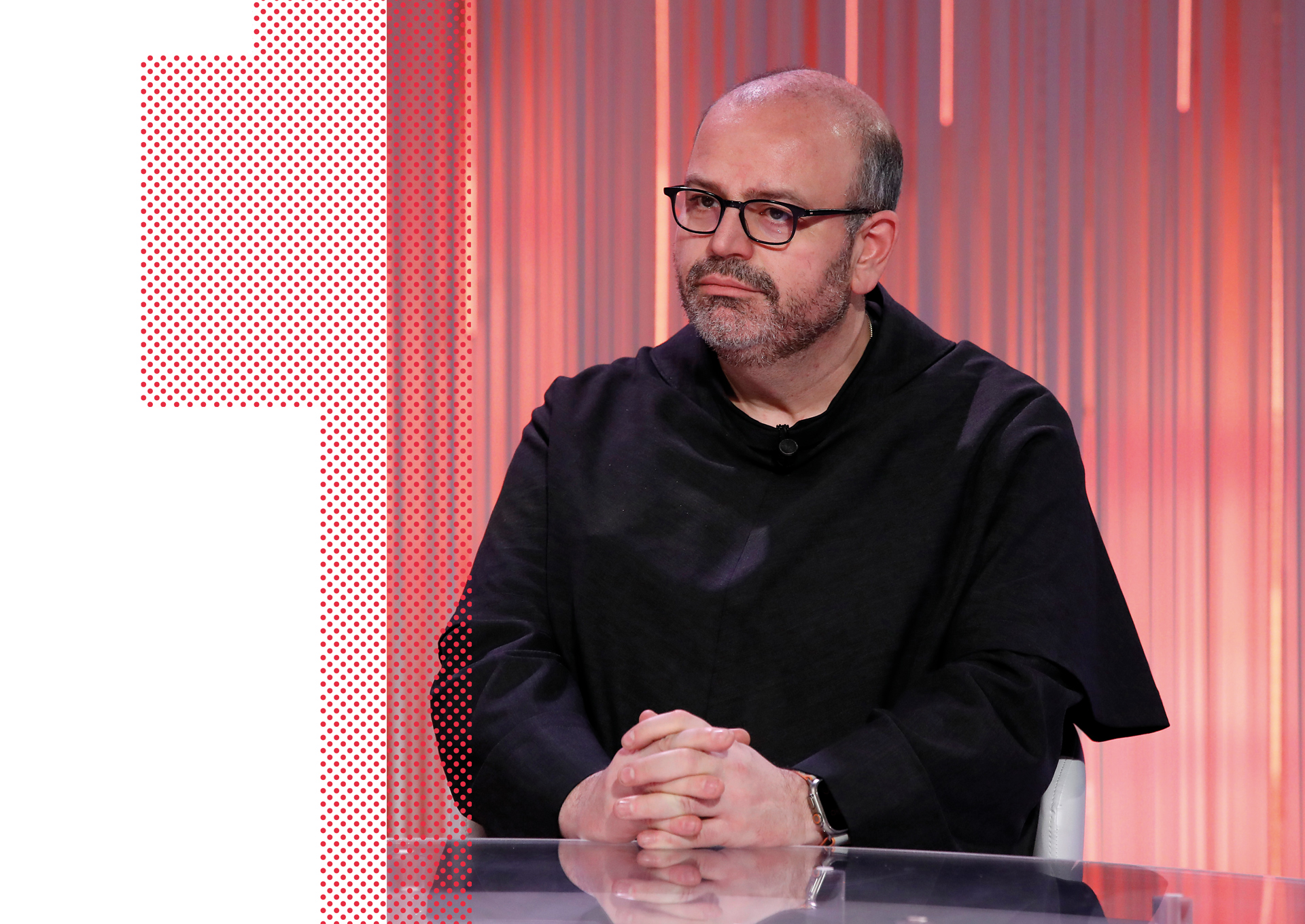 A man with glasses and a beard sits at a clear table, hands clasped, wearing a black top. The background features vertical pink and orange glowing lines and a red dotted pattern on the left side.