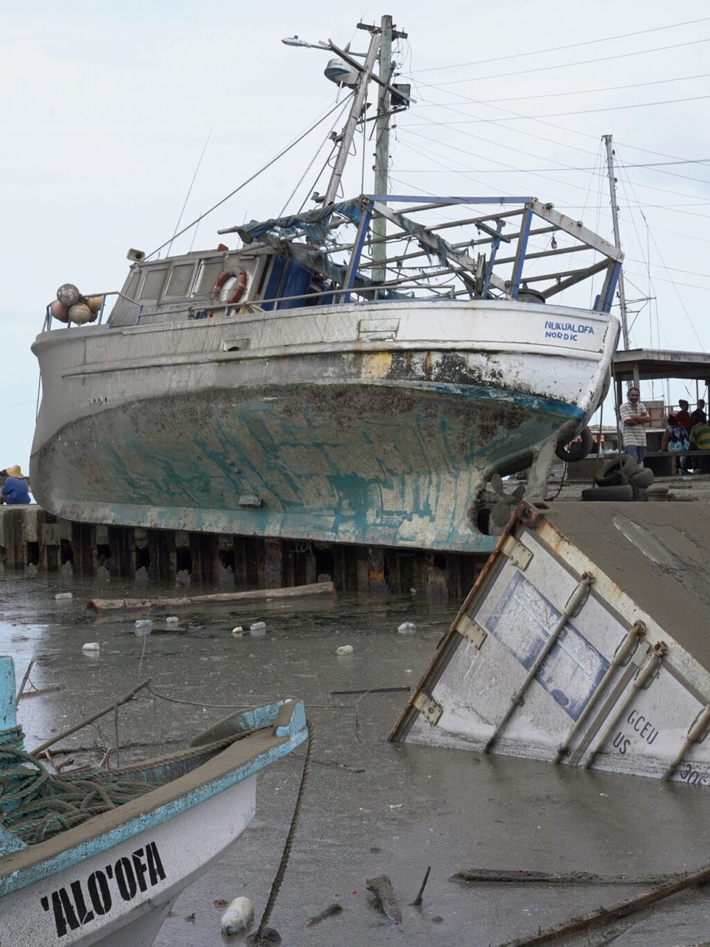 A large boat lies out of the water and near a pier after a tsunami hit.