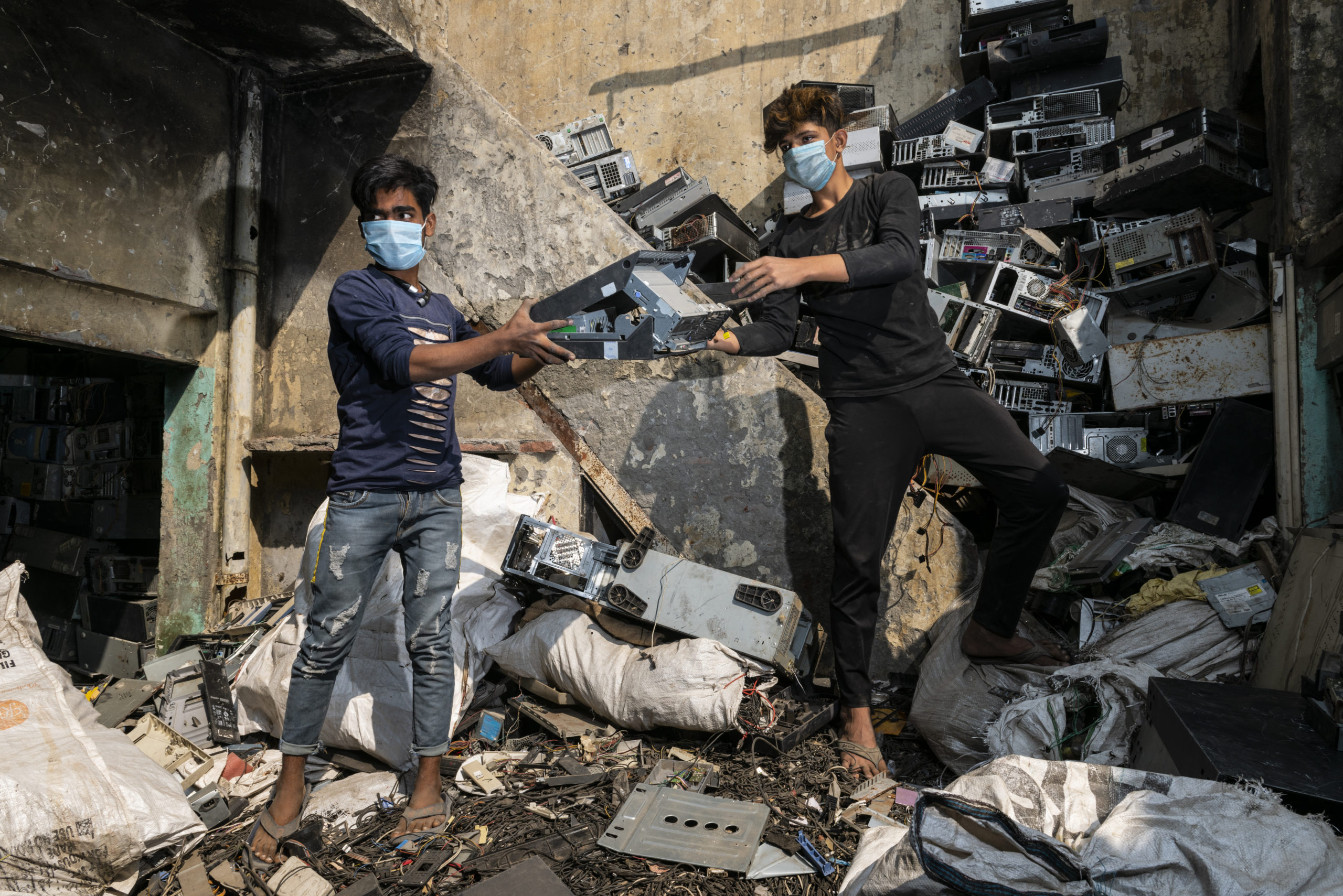 Men standing in a pile of e-waste
