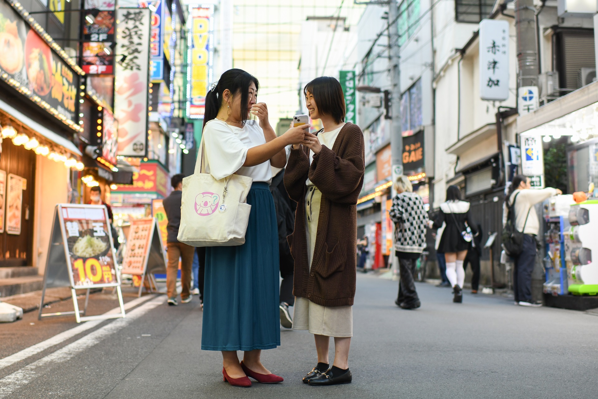 Photo of two women conversing while standing in a street in Tokyo, Japan