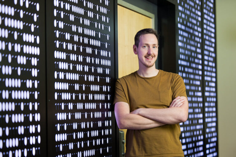 A man with cross arms leaning against a digital wall