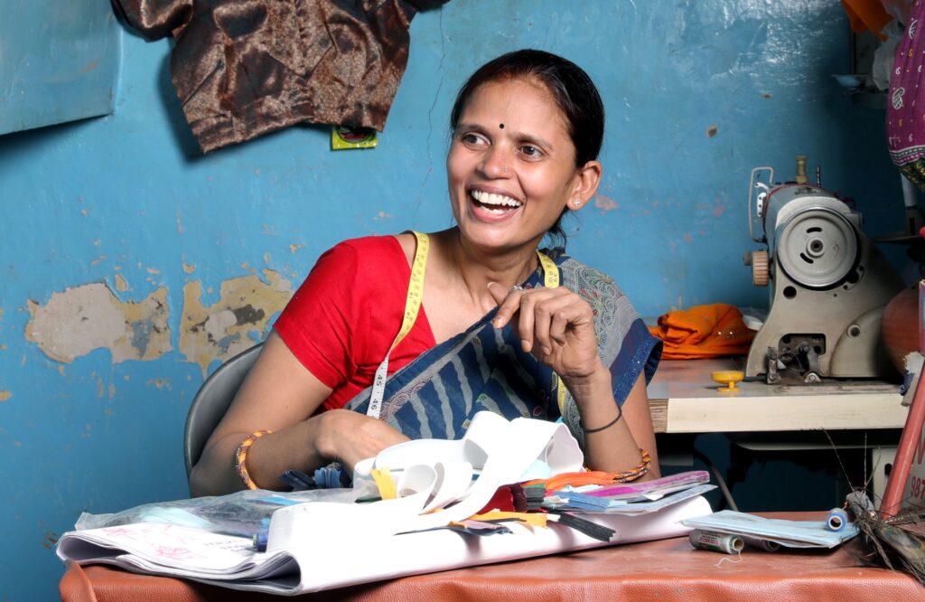 A person smiling at a table in a tailoring shop