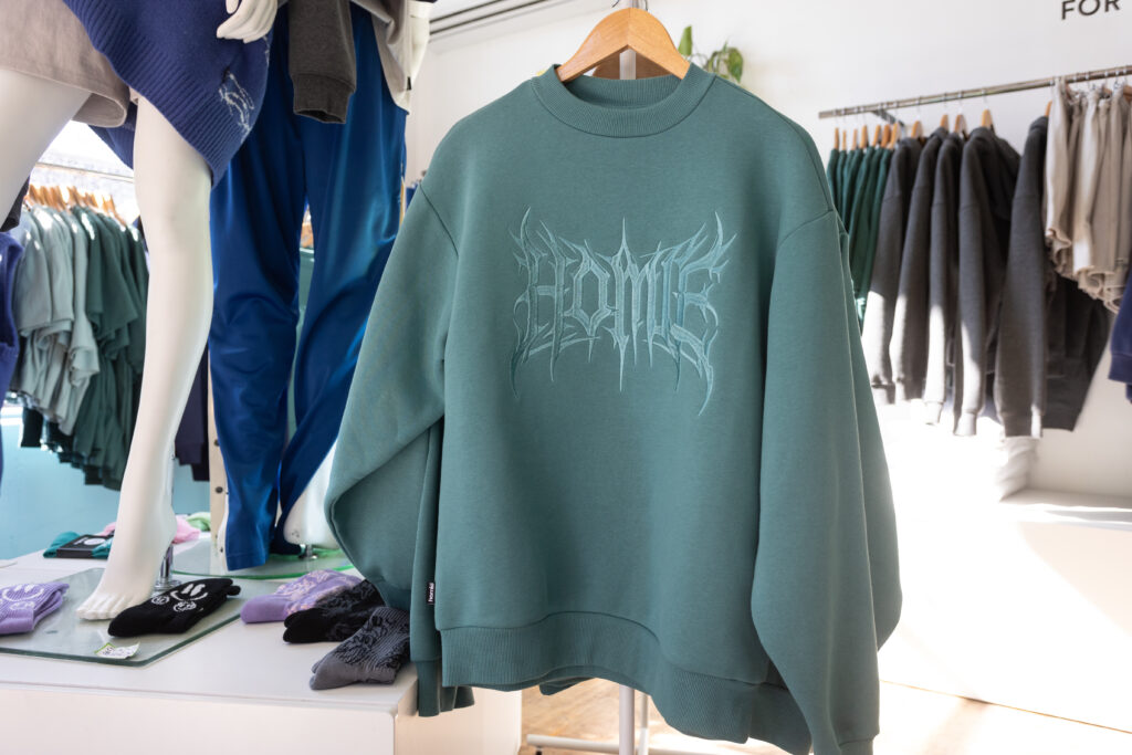 Photo of a green crewneck sweatshirt with the HoMie logo