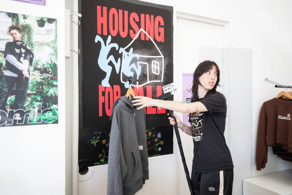 Photo of a girl in a black outfit preparing to display a grey hoodie in a store