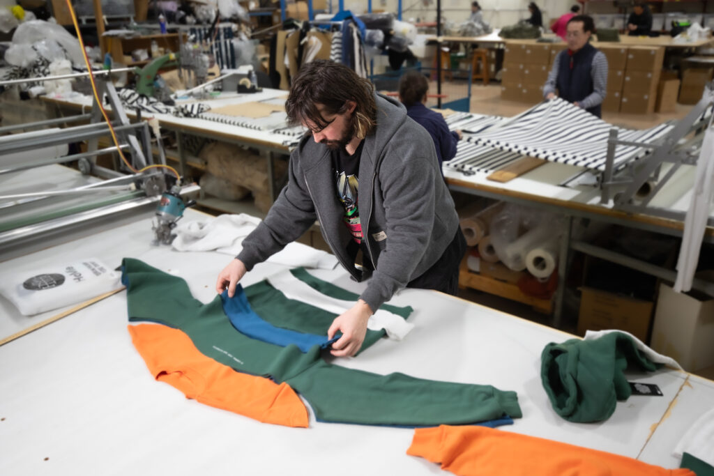 Photo of a man with long hair and beard in the process of making an orange and green sweatshirt