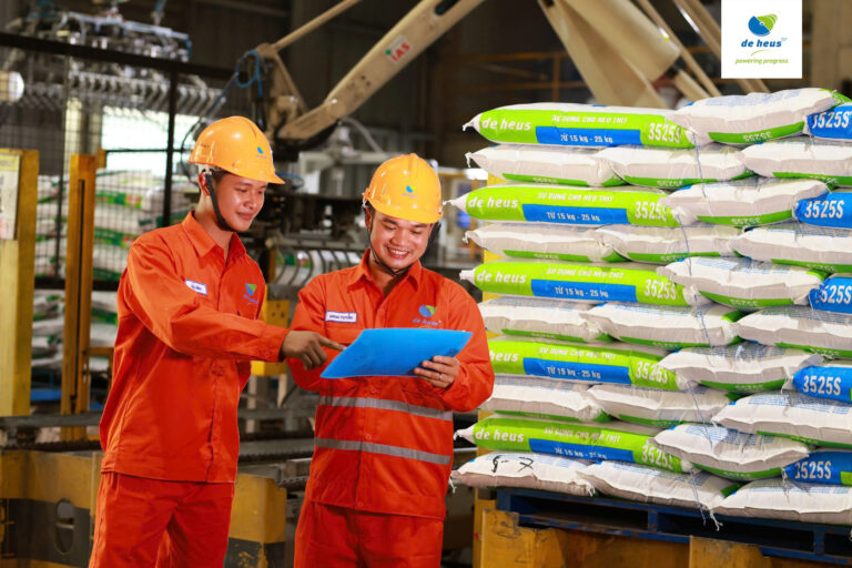 Two standing workers discussing about work at De Heus factory.