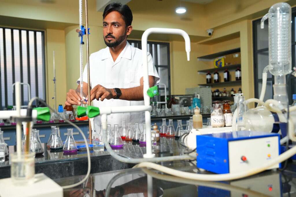 A man in a laboratory working on some tests and experiments with flasks and equipment around him