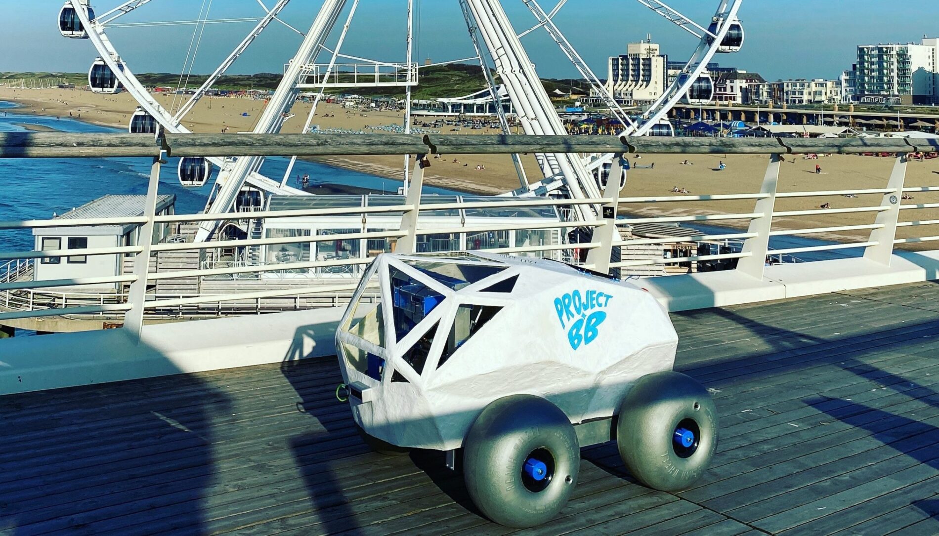 BeachBot sits on a raised boardwalk at Scheveningen Beach with the Ferris wheel in the background