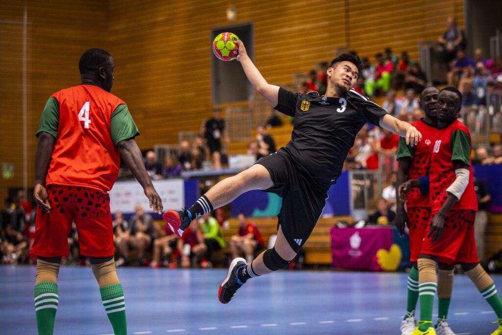 A participant in the Special Olympics catches a handball on court.
