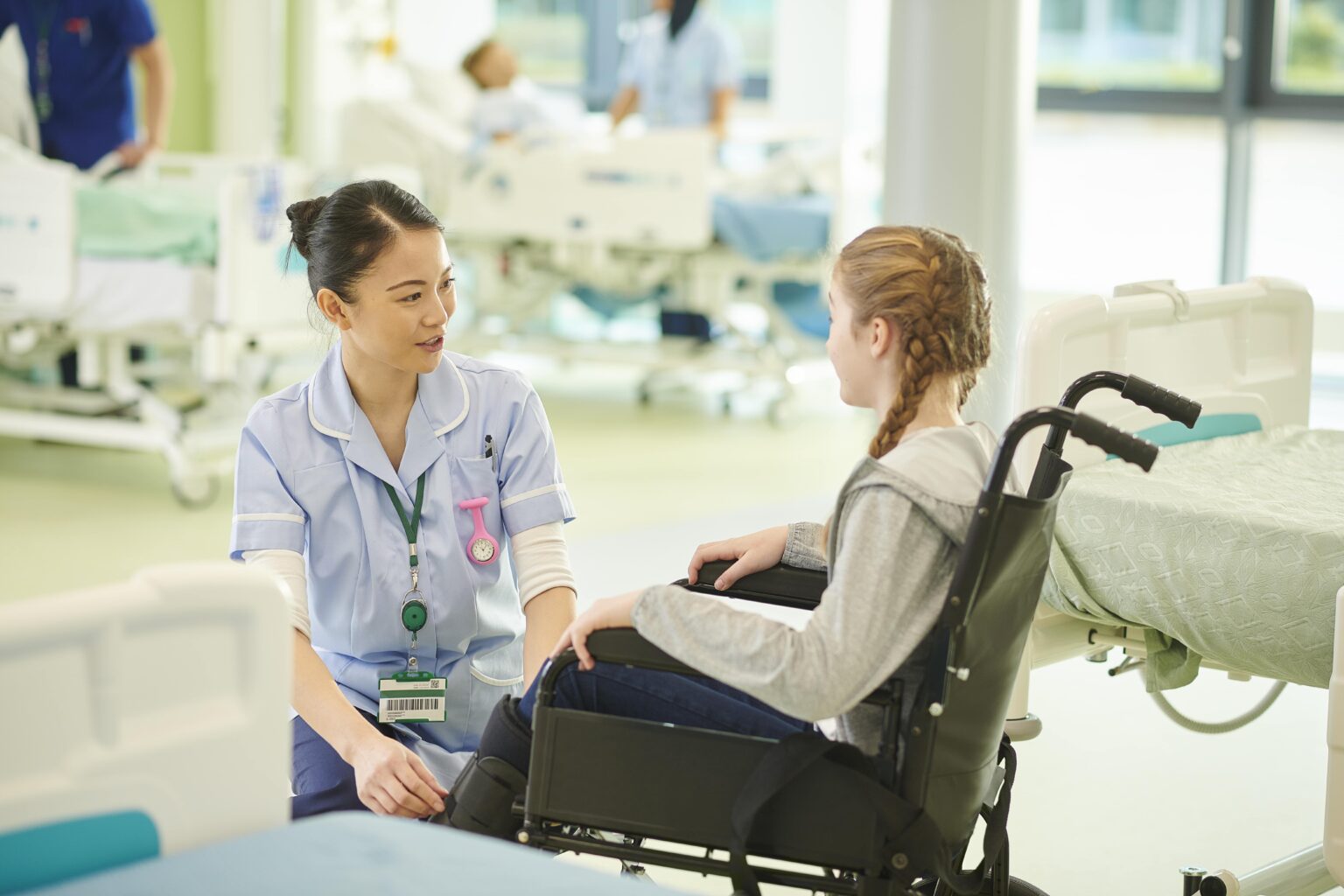 Nurse talking to young woman in wheelchair