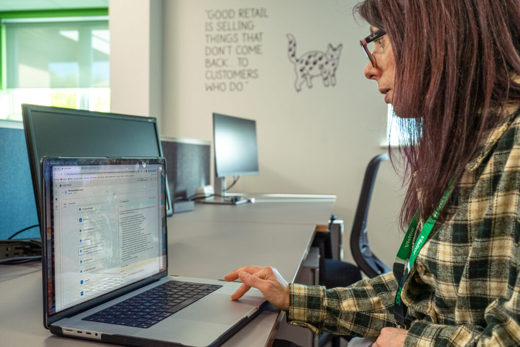 A woman in glasses working at a computer as seen from the side.