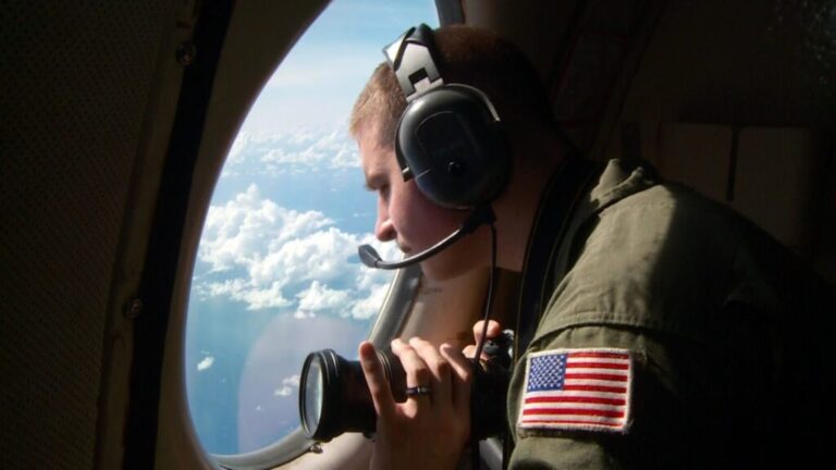 Brandon Yaeger looking out the window of a P-3c Orion equipped for extended search and rescue