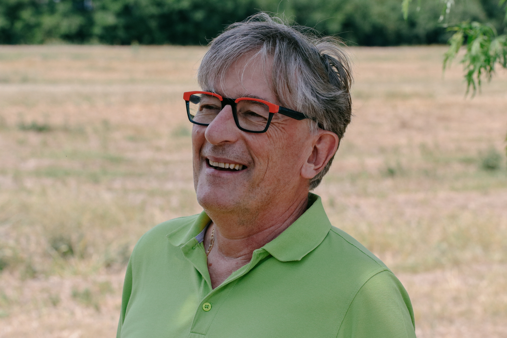 A smiling man in a green polo shirt wearing glasses.