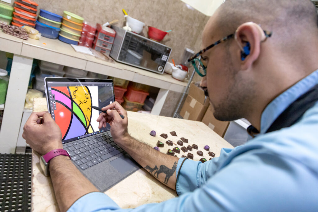 Azgard trabaja en una Microsoft Surface en una cocina con unos chocolates en la mesa